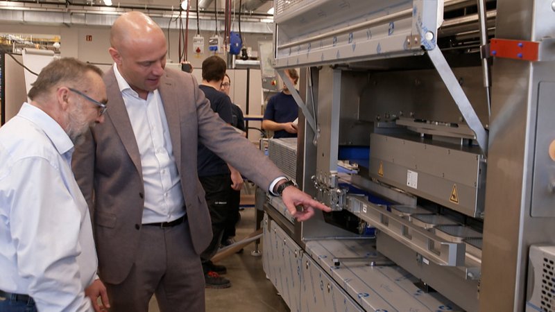 Tobias Richter (rechts) von der Firma Multivac begutachtet mit einem Mitarbeiter eine Maschine, die auch nach Indien exportiert wird. | Bild: BR Tobias Richter (rechts) von der Firma Multivac begutachtet mit einem Mitarbeiter eine Maschine, die auch nach Indien exportiert wird.