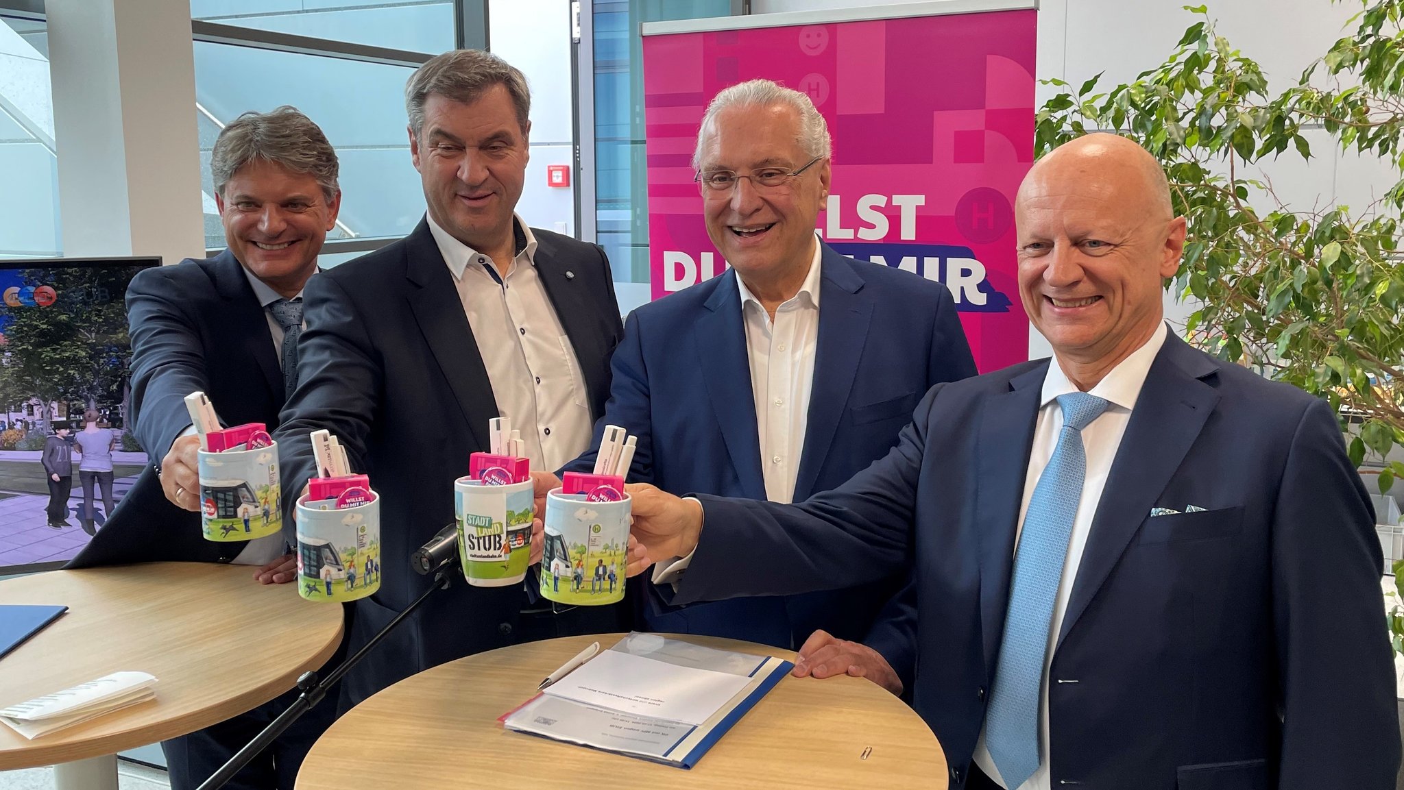 FAU-Präsident Prof. Joachim Hornegger, Ministerpräsident Markus Söder, Verkehrsminister Joachim Herrmann (beide CSU), und Siemens-Finanzvorstand Ralf Thomas (v.l.n.r.) mit StUB-Werbeartikeln in der Hand