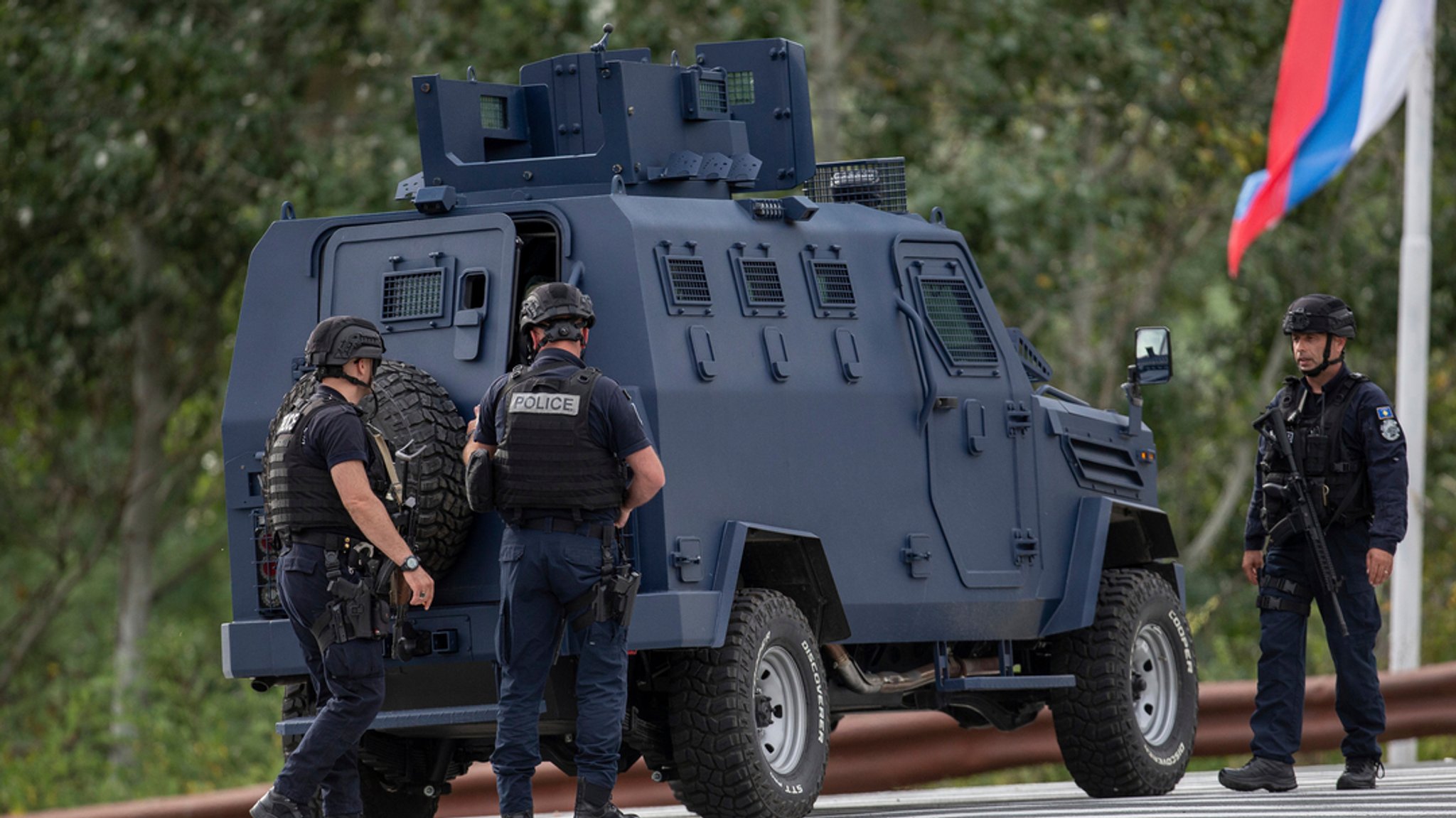 24.09.2023, Kosovo, Banjska: Polizisten aus dem Kosovo sichern eine Querstraße, die zum Banjska-Kloster führt.