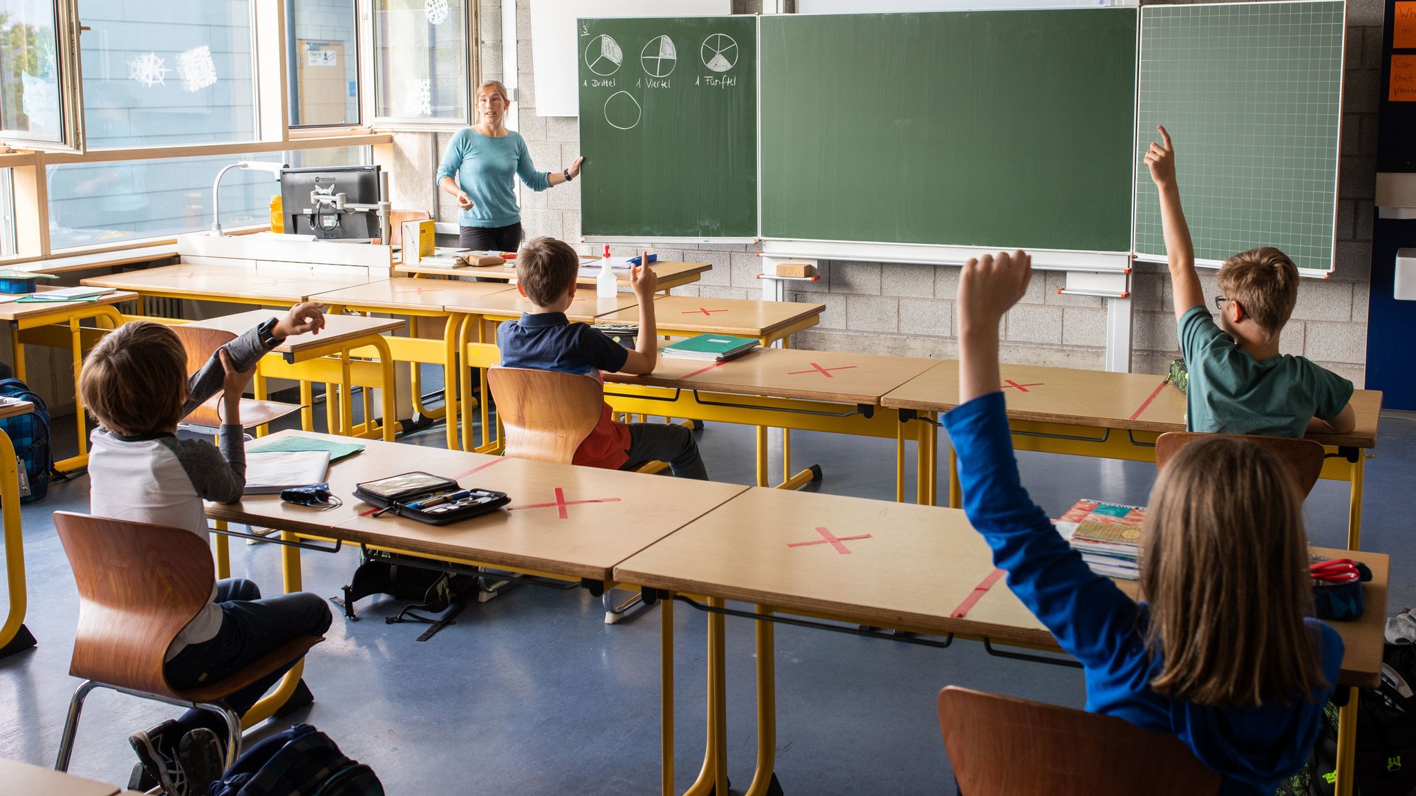 Schülerinnen und Schüler sitzen auf Abstand in einem Klassenzimmer 