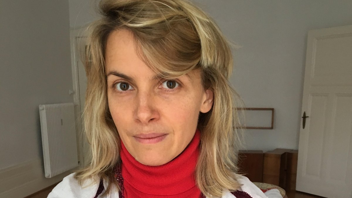 Portrait von Kunsthistorikerin Julia Voss in einem Altbau mit rotem Rollkragenpullover