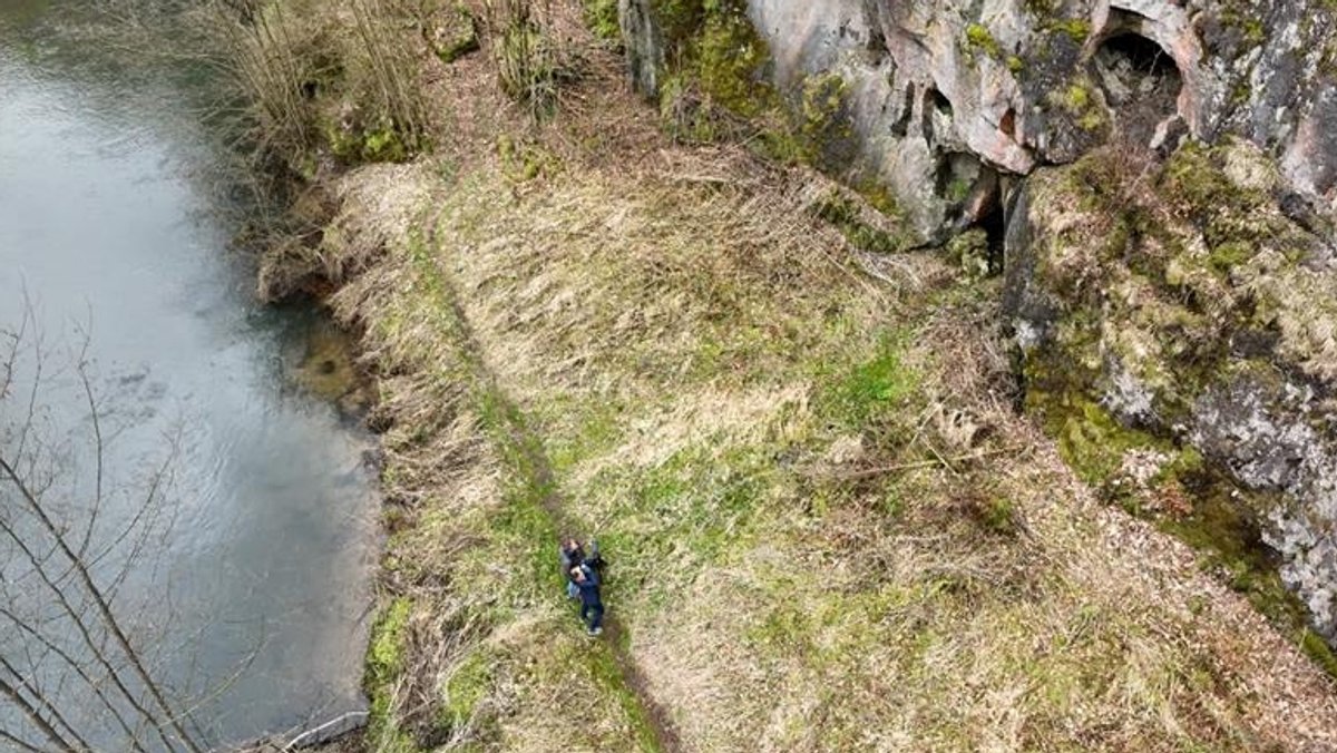 Zwei Menschen stehen vor einer Felswand und beobachten Brutplätze von Wanderfalken.