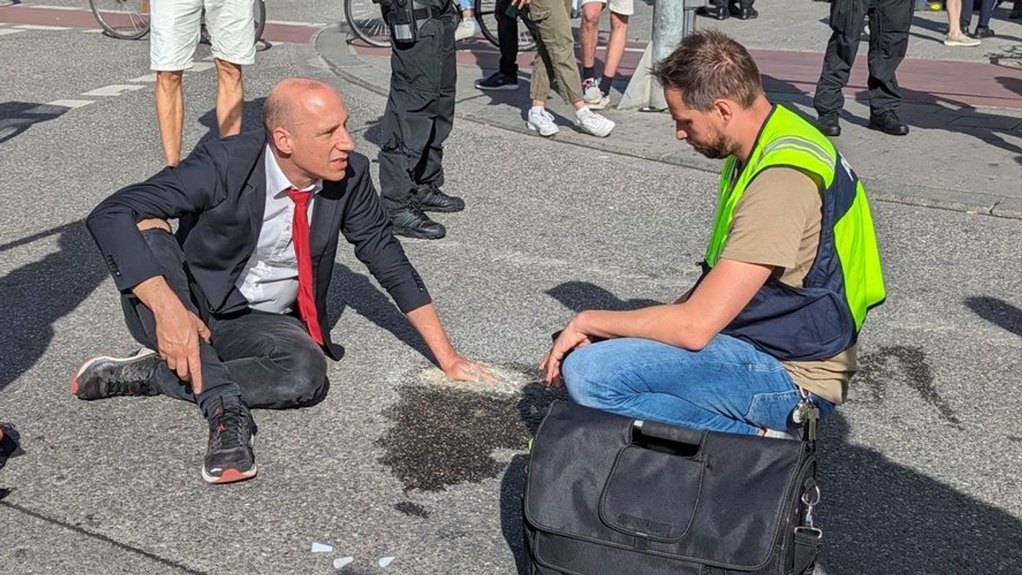 14.07.2023, Bayern, München: Ein Klimaaktivist hat sich mit Zement an einer Fahrbahn auf dem Münchner Karlsplatz (Stachus) fixiert. Die Polizei war dort am Freitag wegen einer Blockadeaktion der Gruppe Letzte Generation im Einsatz. Foto: Anna-Lena Reif/dpa +++ dpa-Bildfunk +++