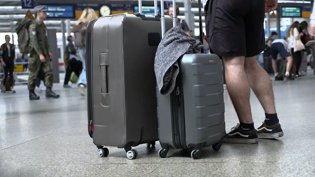 Ein Tourist mit seinen Koffern steht am Hauptbahnhof in München.
