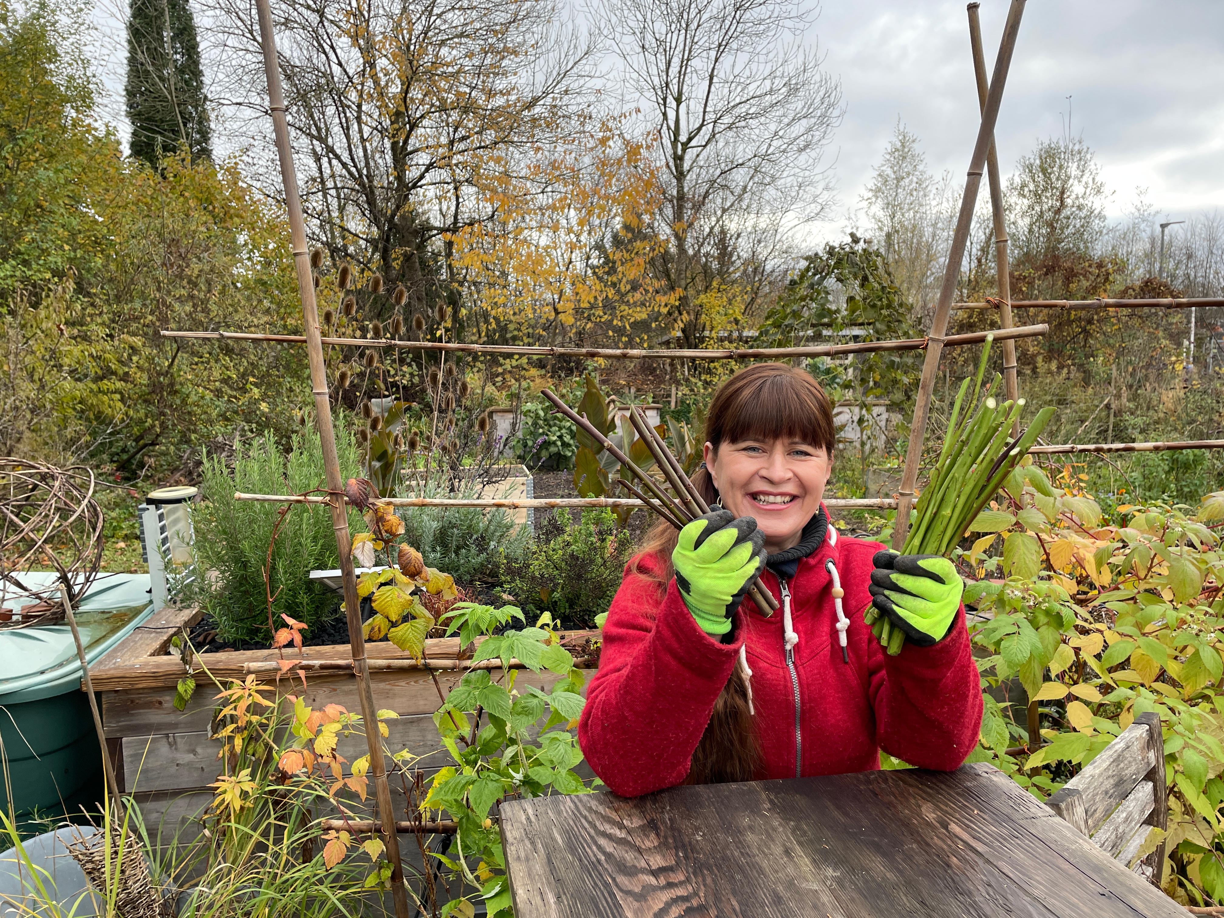 Sabrina Nitsche steht im Querbeet-Garten an einem Tisch mit Steckhölzern in der Hand.