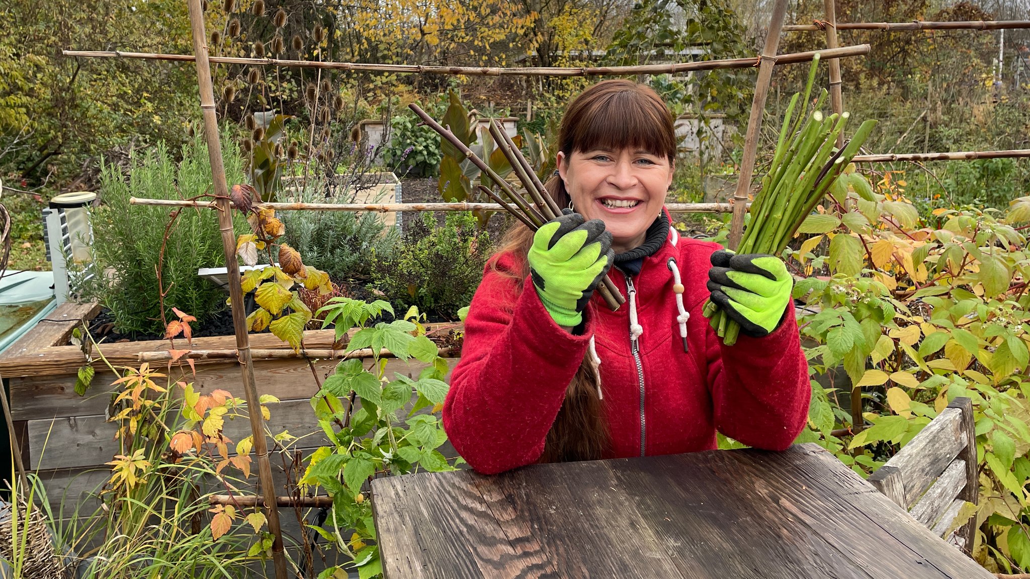 Sabrina Nitsche steht im Querbeet-Garten an einem Tisch mit Steckhölzern in der Hand.