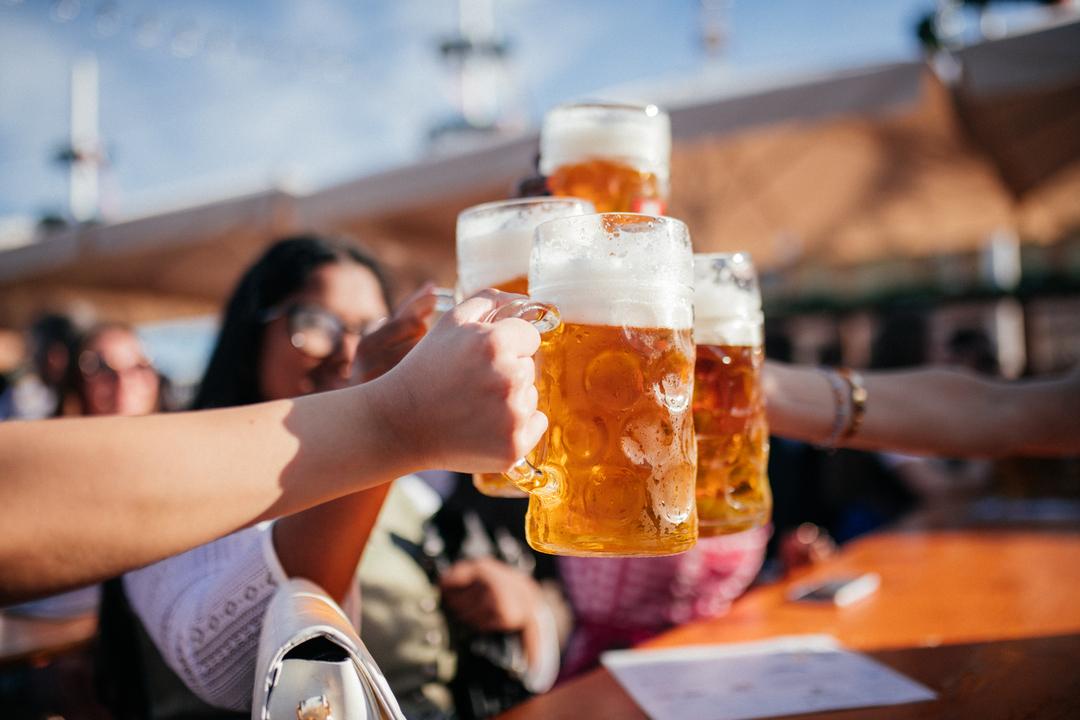 Menschen stoßen auf dem Oktoberfest mit Bier an. 