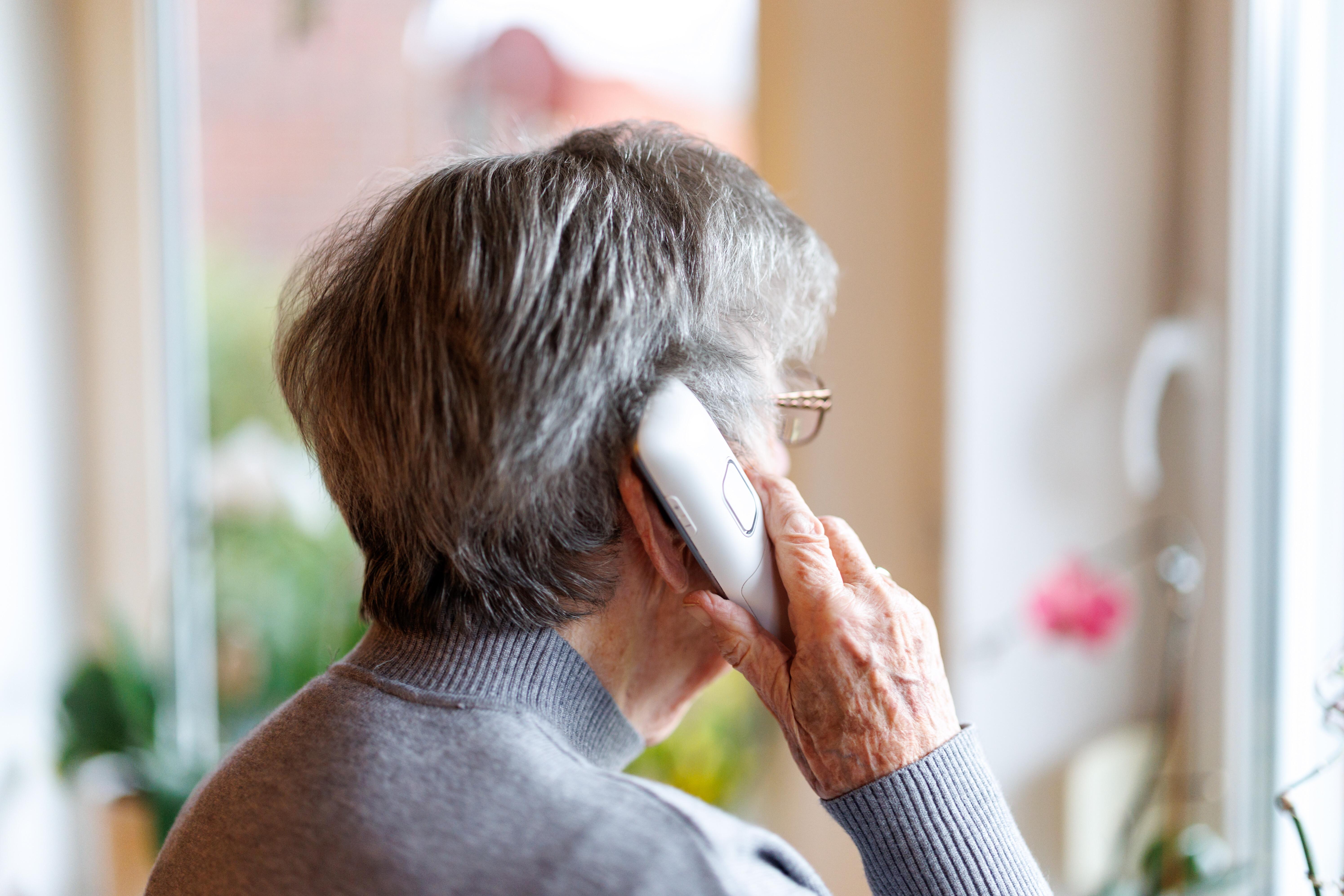 (Symbolbild) Eine Frau telefoniert, während sie aus dem Fenster blickt. 