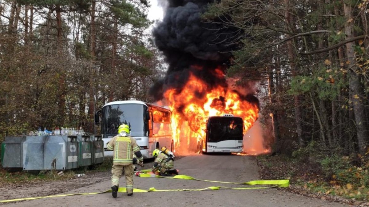 Die brennenden Busse auf einem Parkplatz bei Unterschleißheim, Kräfte der Feuerwehr mit Atemschutz.
