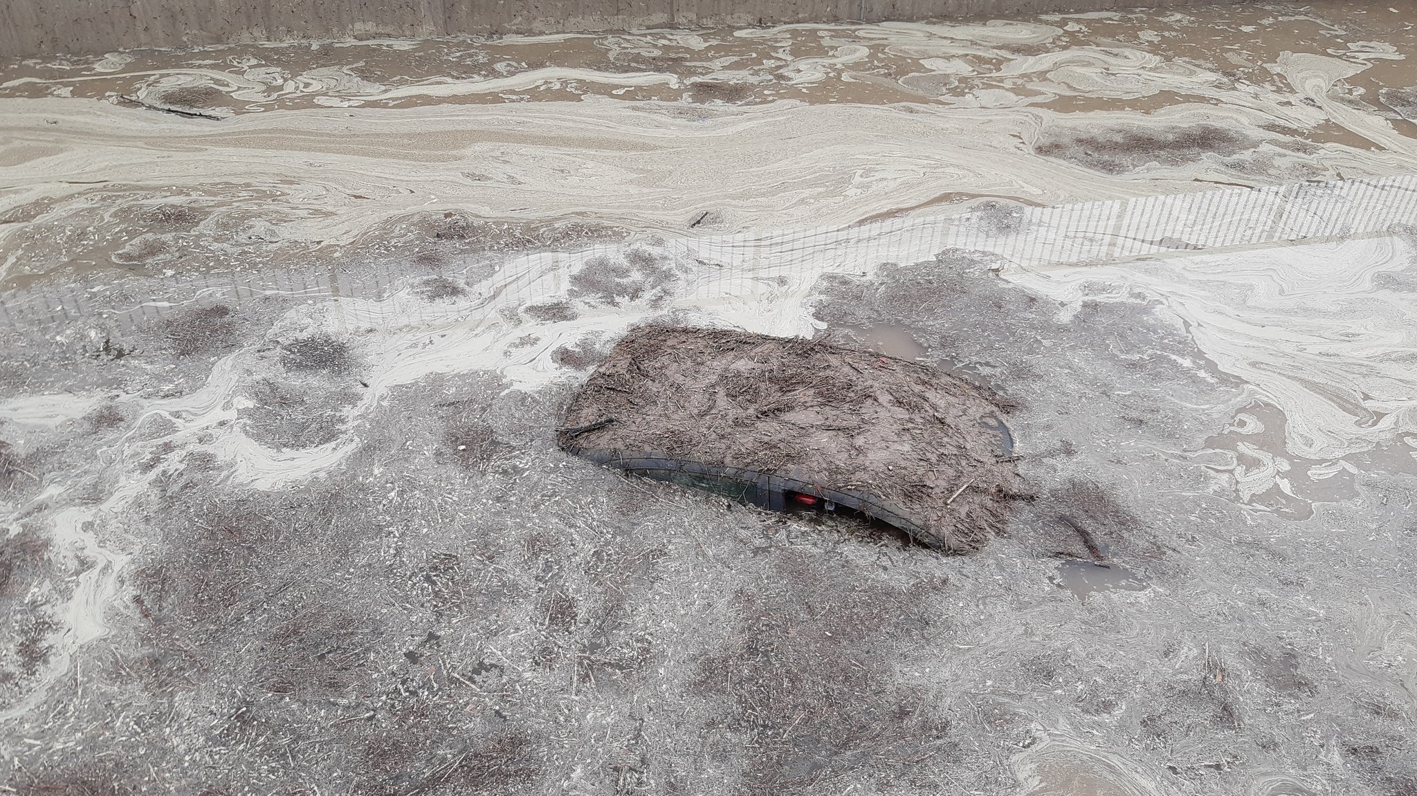 Nur das verdreckte Autodach schaut aus schlammigen Wassermassen heraus.