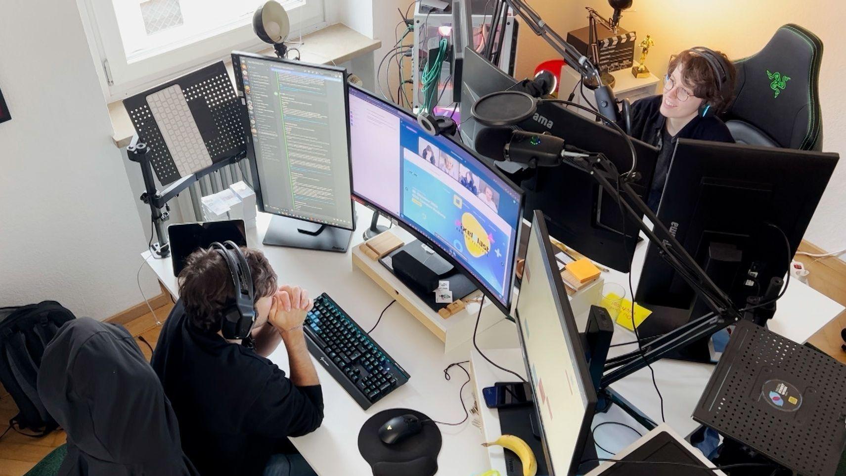 Nando Petri und Katha Röhrl in ihrem Büro vor Bildschirmen