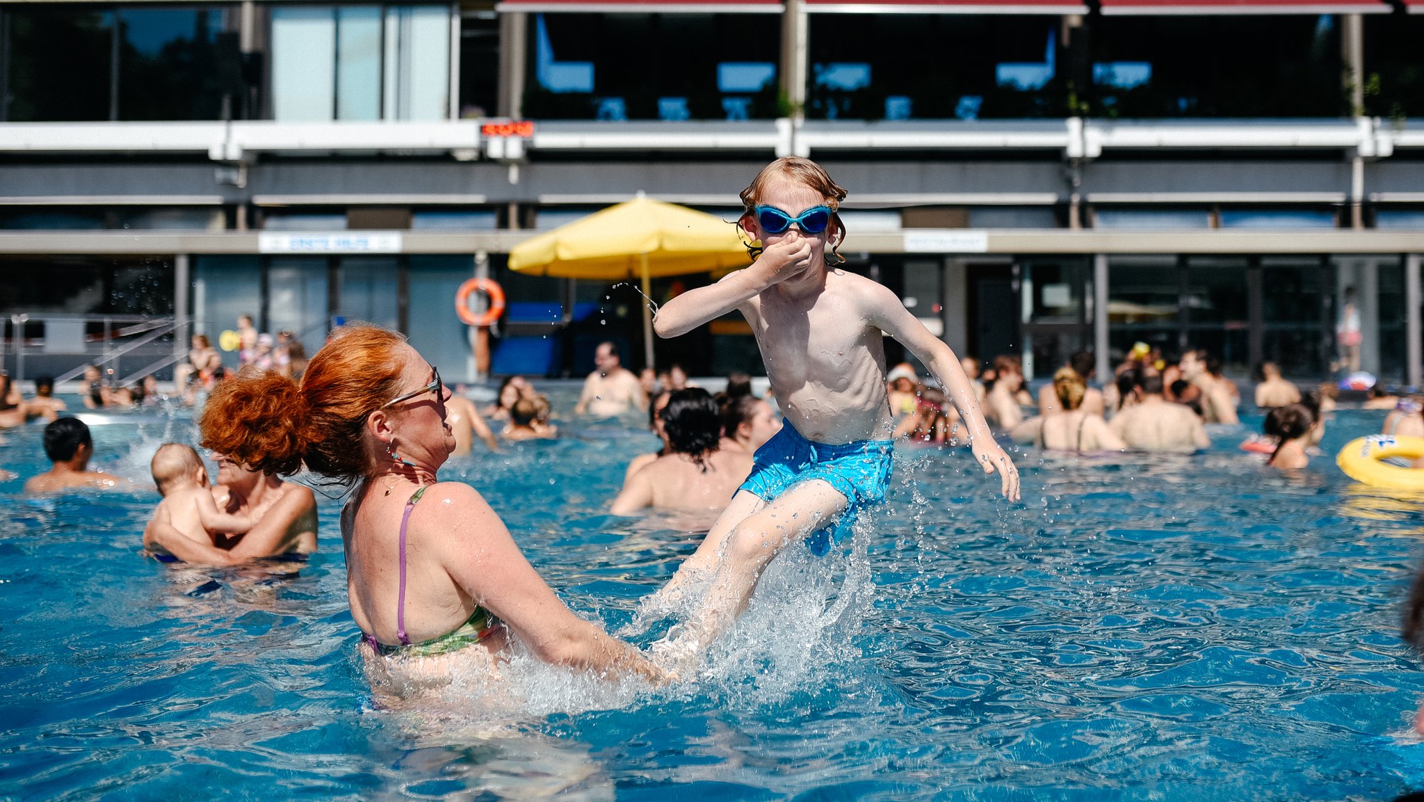 Eine Mutter plantscht mit ihrem Sohn im Schwimmbad.