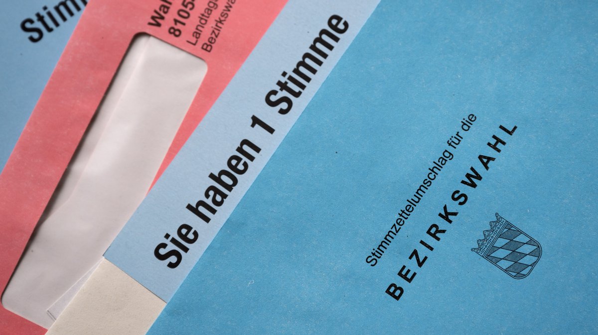 Auf einem Tisch liegen aufgefächert Briefwahlunterlagen für die Landtags- und die Bezirkswahl 2023 in Bayern. 