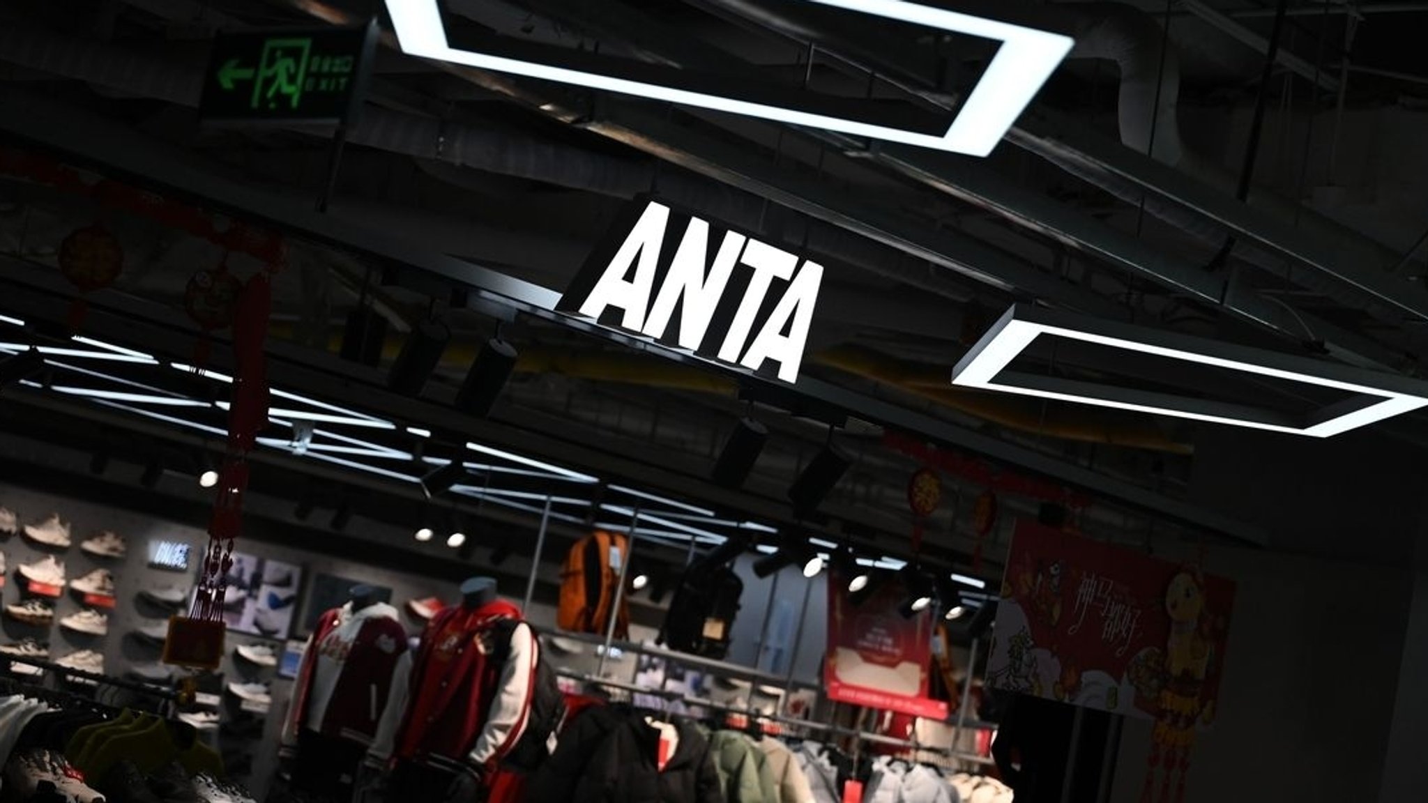 Das Logo des chinesischen Sportartikel-Konzerns Anta Sports hängt an einem Ladeneingang in einer Mall.