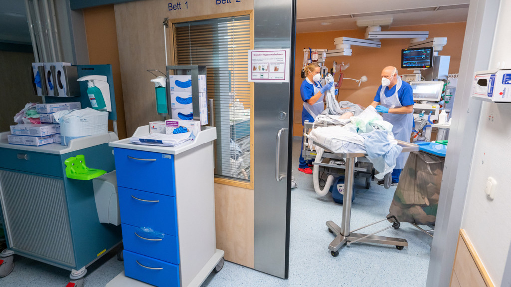 Bayern, Gauting: Zwei Pflegekräfte arbeiten in Schutzkleidung mit einem Patienten in einem Intensivbett-Zimmer der Asklepios Klinik. (4.11.21)