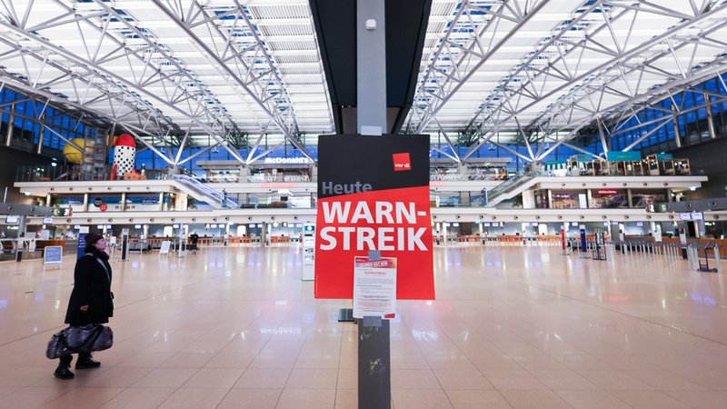 Ein Schild mit der Aufschrift "Warnstreik" hängt im Flughafen Hamburg. | Bild: dpa-Bildfunk/Christian Charisius Ein Schild mit der Aufschrift "Warnstreik" hängt im Flughafen Hamburg.