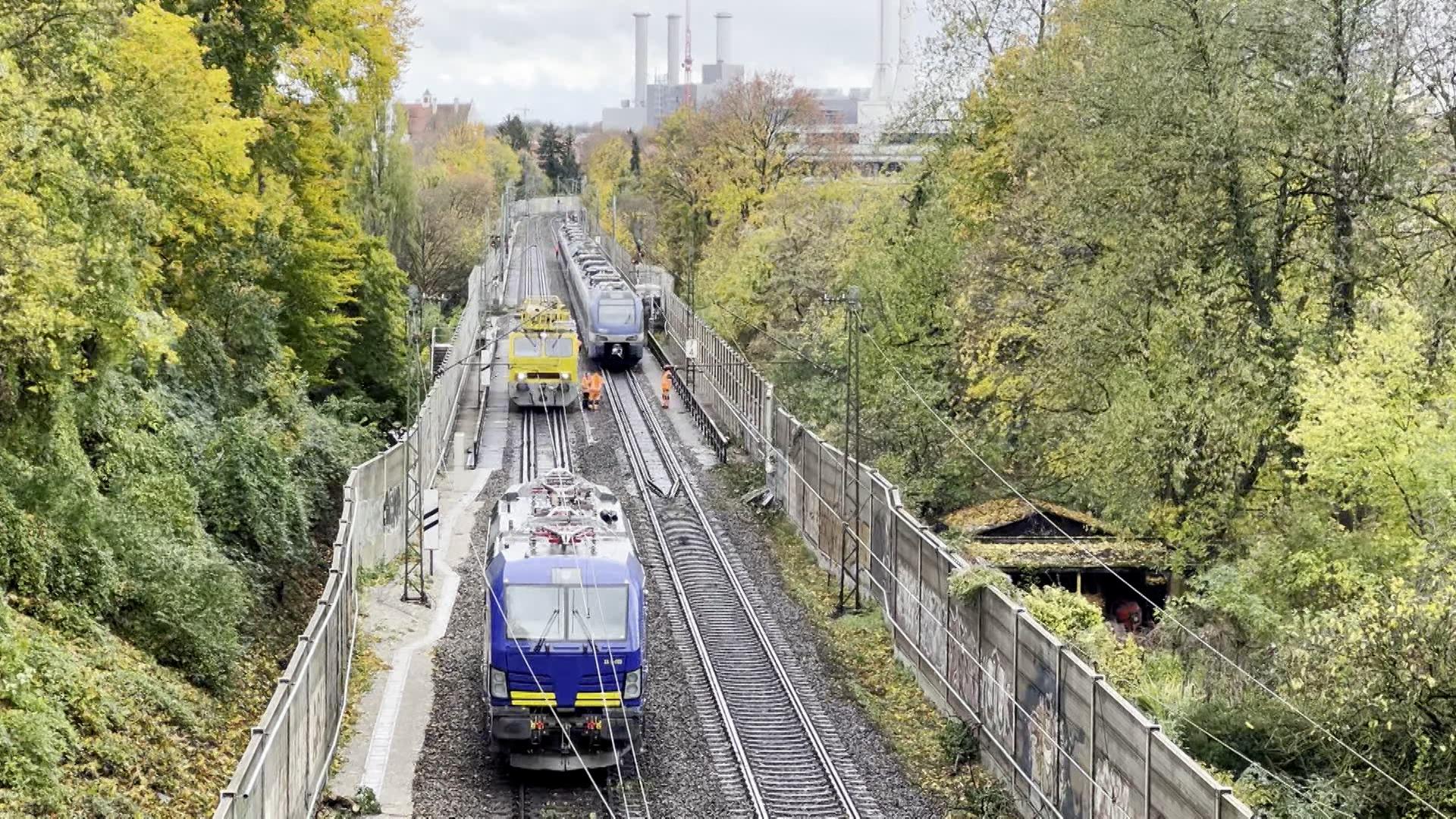 Stehende Züge auf Gleisen, gesäumt von Lärmschutzwänden