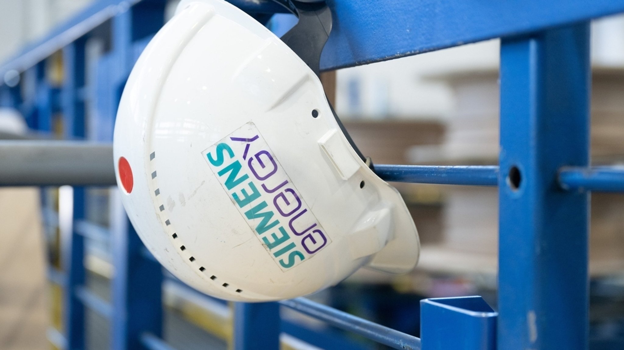 Ein Schutzhelm mit der Aufschrift Siemens Energy hängt in einer Werkhalle des Konzerns