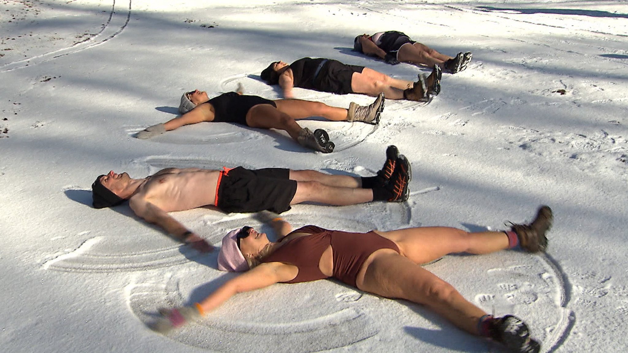 Fünf Menschen liegen im Bikini im Schnee