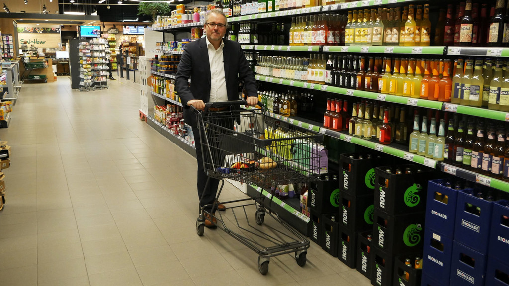Karsten Kilian geht mit Einkaufswagen durch die Supermarktgänge. 