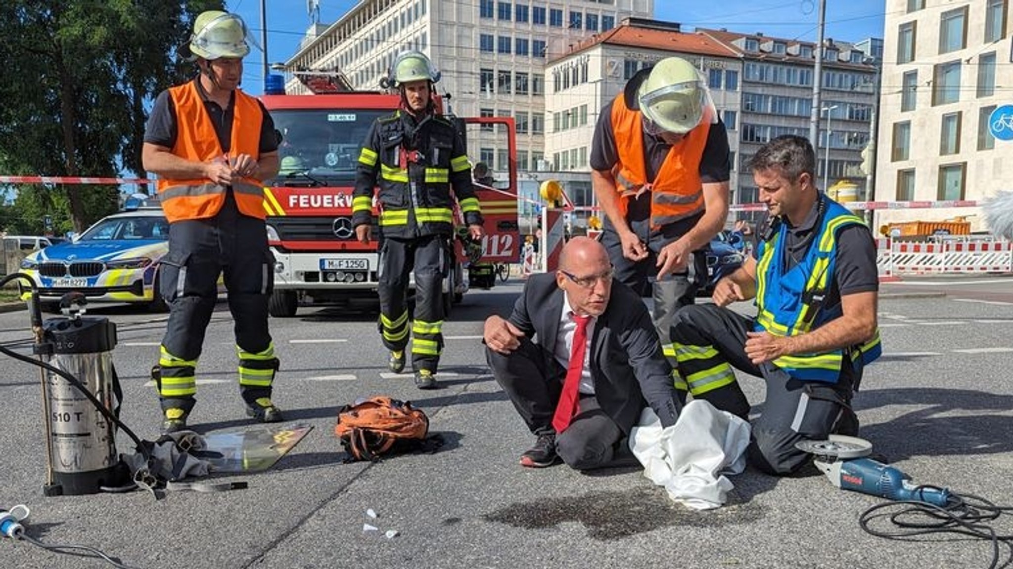 14.07.2023, Bayern, München: Ein Klimaaktivist hat sich mit Zement an einer Fahrbahn auf dem Münchner Karlsplatz (Stachus) fixiert. Die Polizei war dort am Freitag wegen einer Blockadeaktion der Gruppe Letzte Generation im Einsatz. Foto: Anna-Lena Reif/dpa +++ dpa-Bildfunk +++