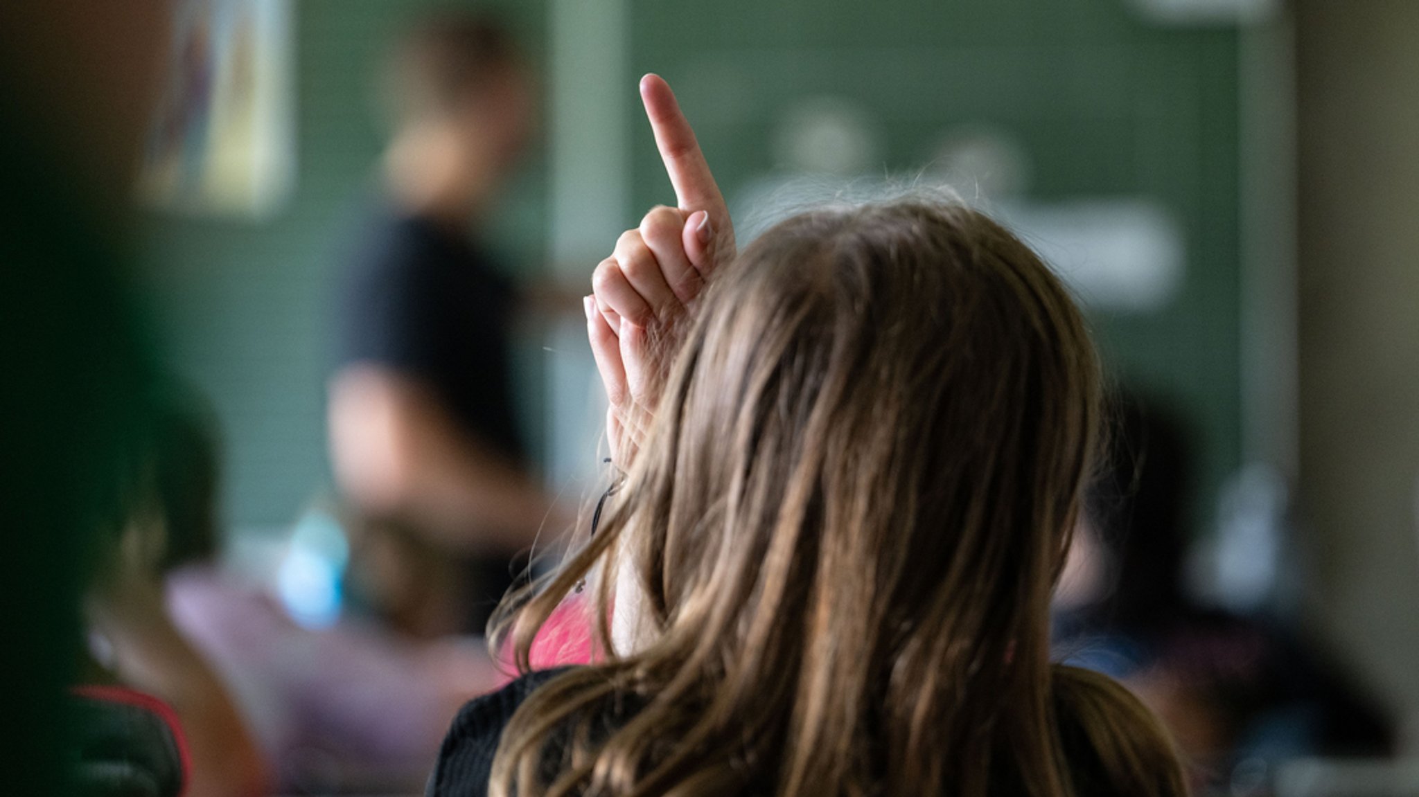 Schülerinnen und Schüler einer vierten Klasse einer Grundschule nehmen am Unterricht teil, eine Schülerin meldet sich. 