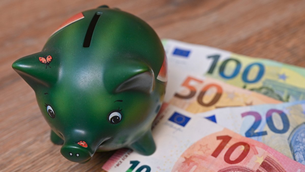 Ein Sparschwein steht auf einem Tisch neben Eurobanknoten