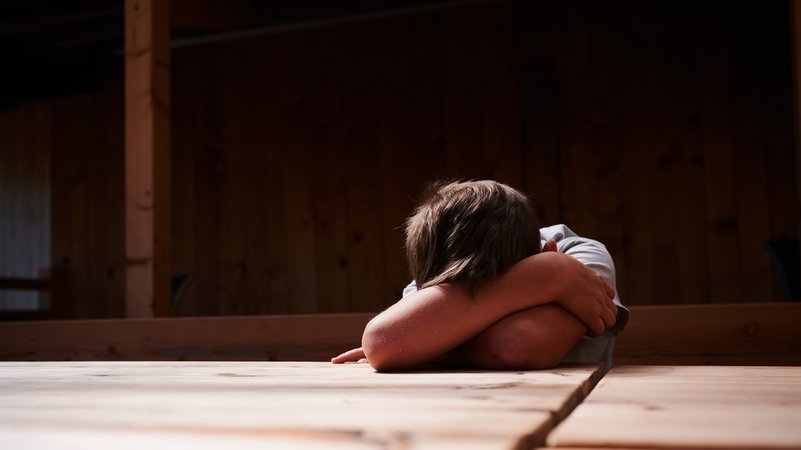 Ein Kind versteckt sein Gesicht unter seinen Armen und liegt mit dem Kopf auf einem Tisch. | Bild: picture alliance/dpa | Annette Riedl Ein Kind versteckt sein Gesicht unter seinen Armen und liegt mit dem Kopf auf einem Tisch.