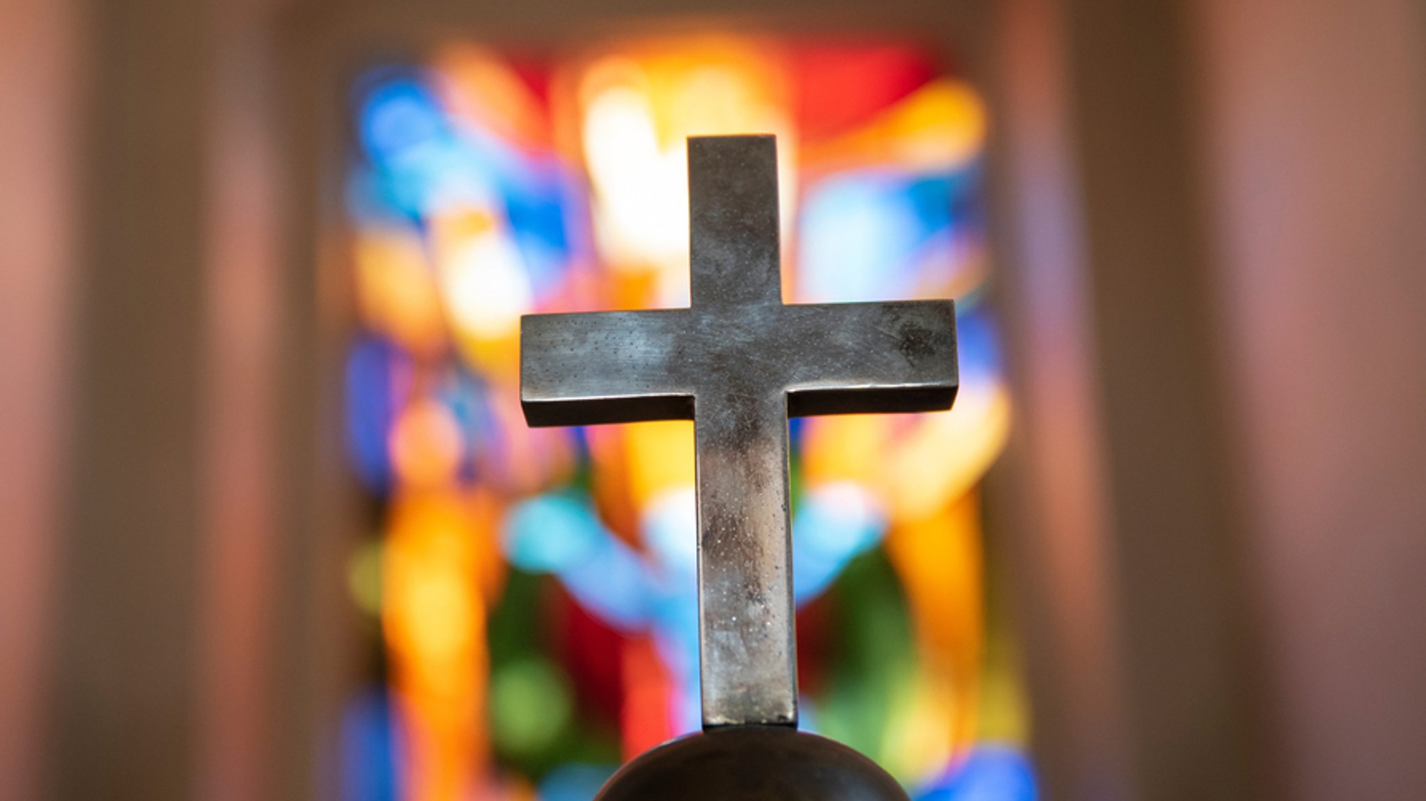 Ein Kreuz steht vor dem Fenster einer Kirche. 