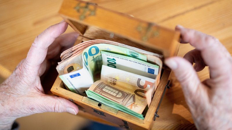 Symbolbild: Jemand zählt mehrere hundert Euro in Geldscheinen in einer kleinen Schatztruhe ab. | Bild: picture alliance / Matthias Balk | Matthias Balk Symbolbild: Jemand zählt mehrere hundert Euro in Geldscheinen in einer kleinen Schatztruhe ab.