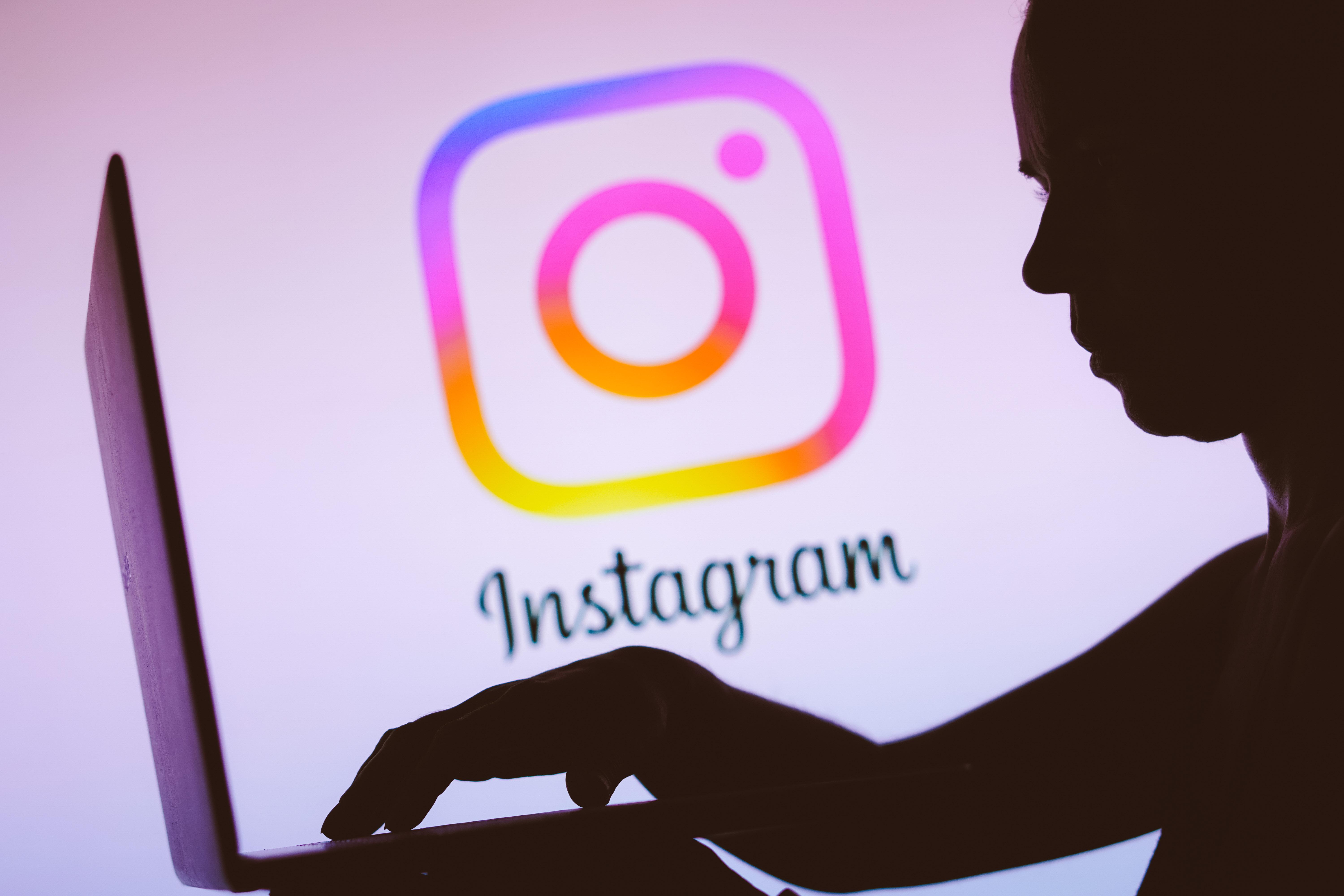 Silhouette einer Person, die vor einem Laptop vor dem Instagram-Logo sitzt. 
