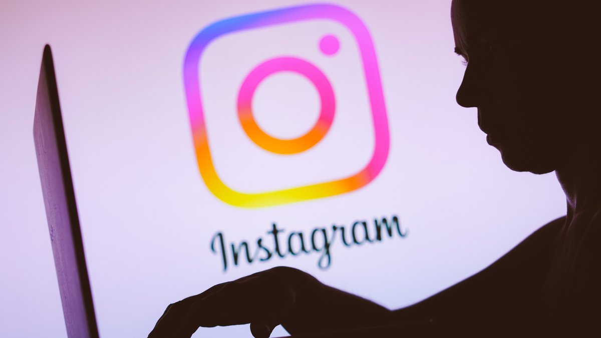Silhouette einer Person, die vor einem Laptop vor dem Instagram-Logo sitzt. 