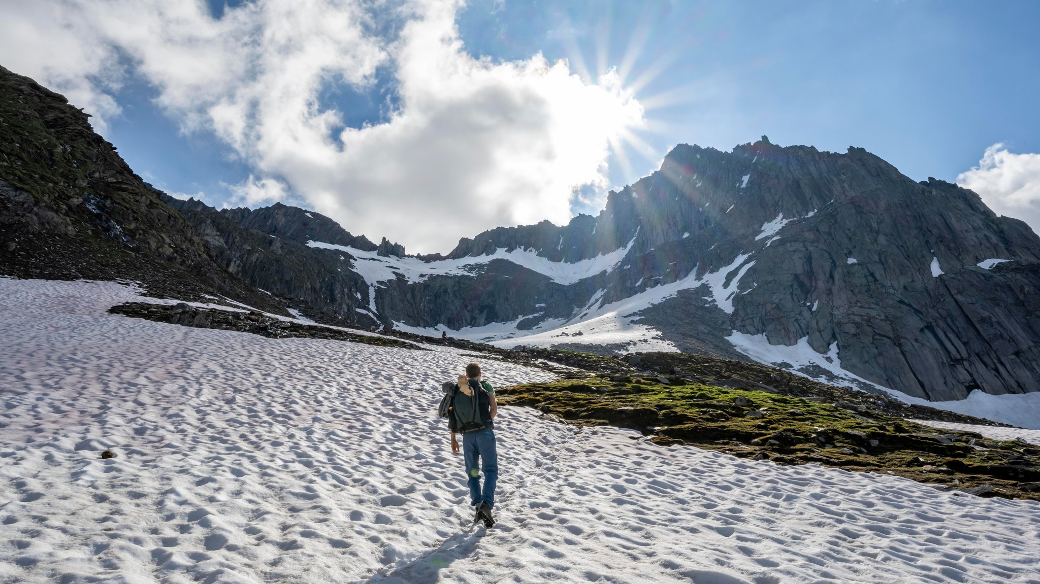 Übergangszeit in den Bergen: Wandern zwischen Altschneefeldern und Gras.