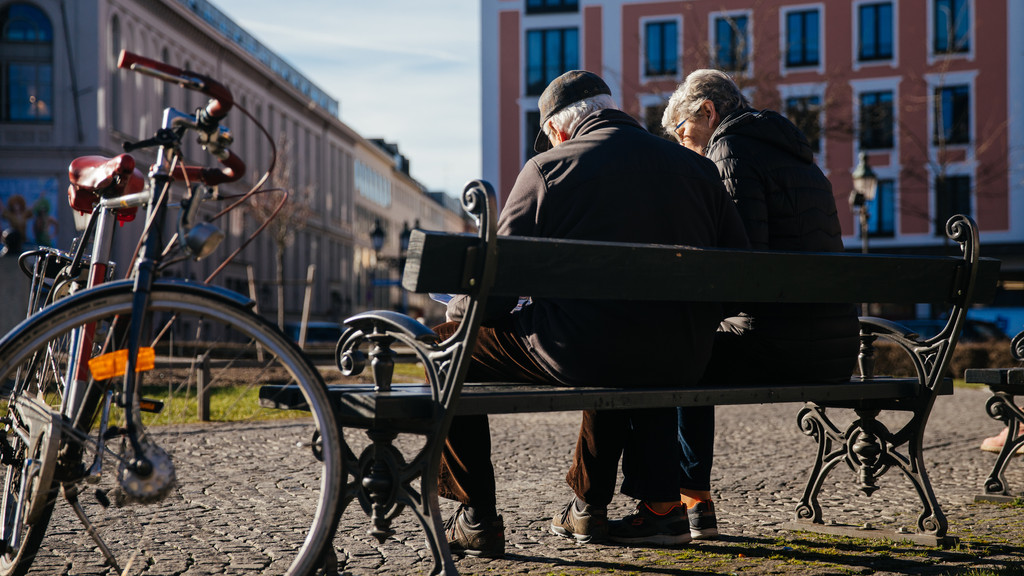 Zwei Senioren auf einer Parkbank am Münchner Gärtnerplatz.