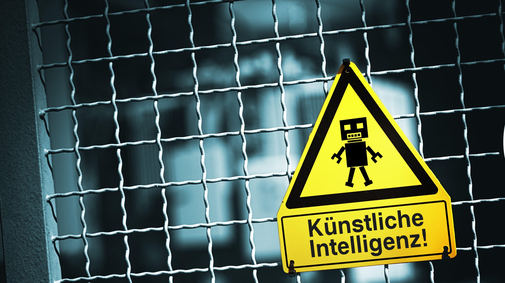 Symbolbild: Roboterfigur auf einem Warnschild mit Aufschrift Künstliche Intelligenz