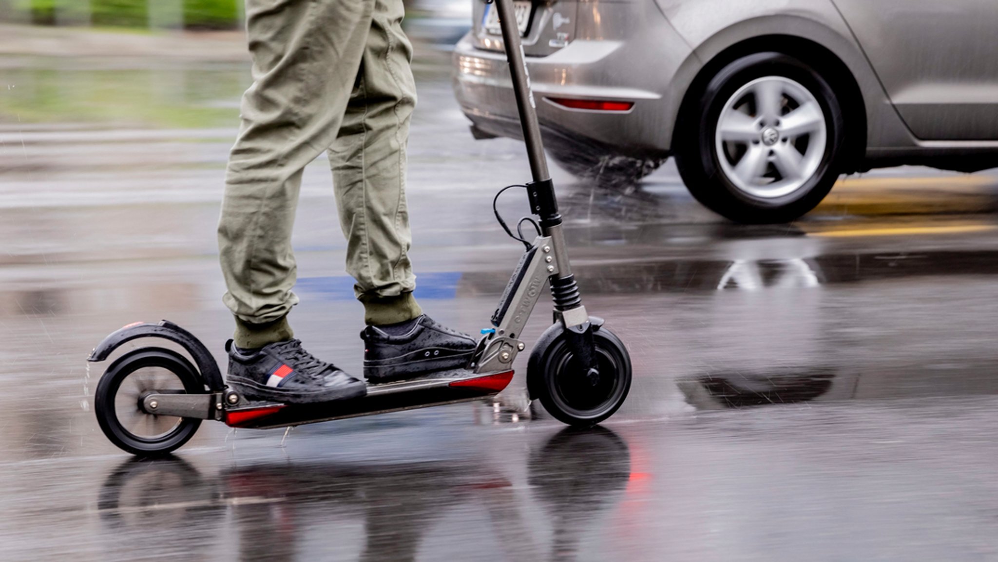 Ein Mann fährt mit einem E-Scooter auf der Straße.