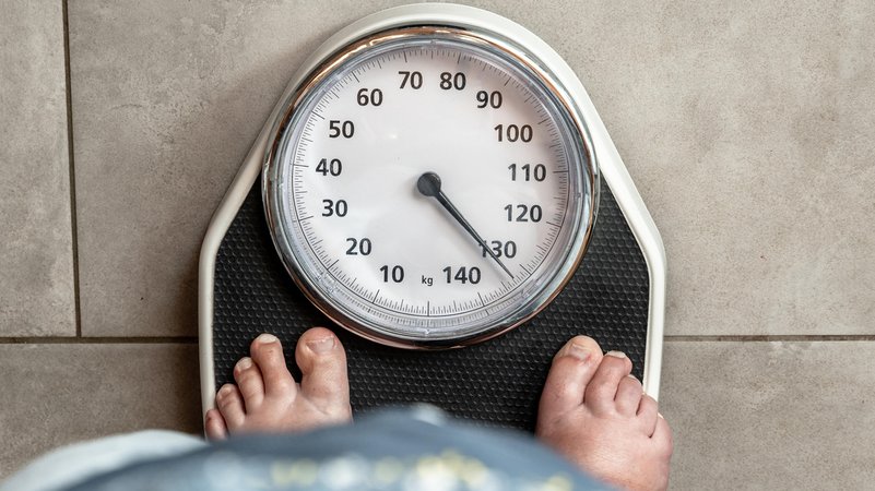 Symbolbild: Eine Person steht barfuß auf einer Waage, die mehr als 130 Kilogramm anzeigt.Gesundheit und Übergewicht | Bild: picture alliance / CHROMORANGE | Michael Bihlmayer Symbolbild: Eine Person steht barfuß auf einer Waage, die mehr als 130 Kilogramm anzeigt.Gesundheit und Übergewicht
