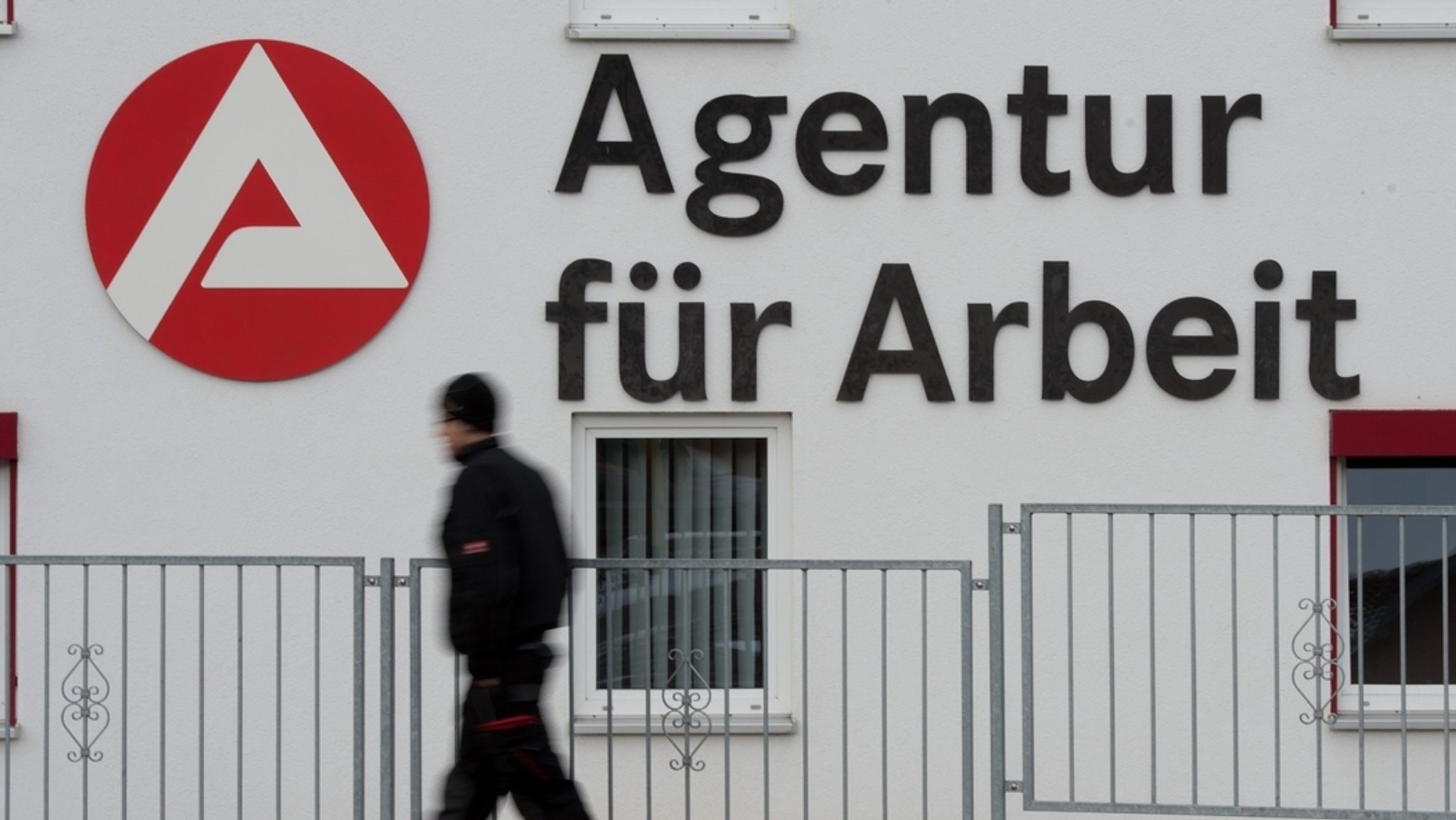 Ein Passant geht an dem Logo der Agentur für Arbeit vorbei.