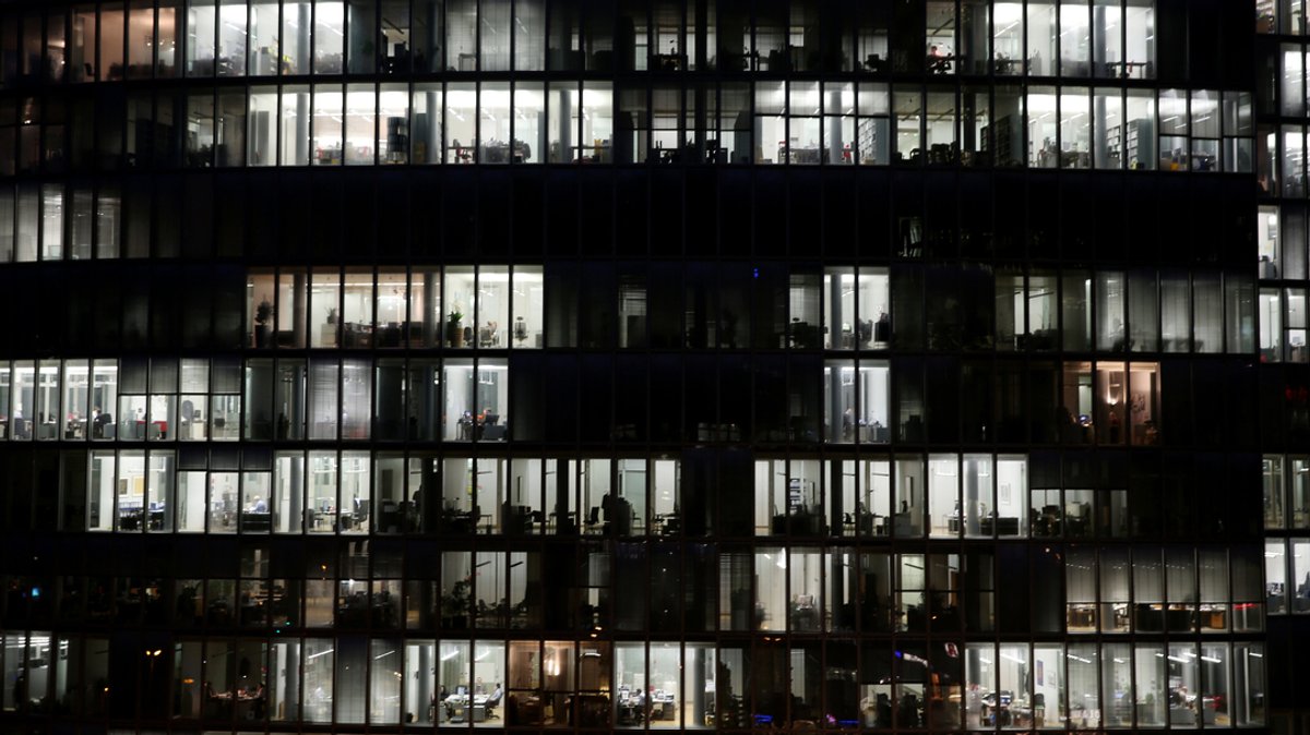 In einem Bürohochhaus sind am Abend zahlreiche Büros beleuchtet, in denen noch gearbeitet wird. 