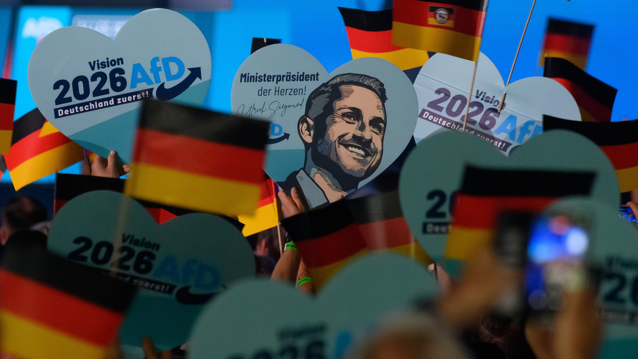 Teilnehmer warten auf den Beginn des Wahlkampfauftakts der AfD Sachsen-Anhalt und schwenken Deutschlandfahnen und halten Herzen mit dem Porträt des Spitzenkandidaten hoch. | Bild: picture alliance/dpa | Klaus-Dietmar Gabbert Teilnehmer warten auf den Beginn des Wahlkampfauftakts der AfD Sachsen-Anhalt und schwenken Deutschlandfahnen und halten Herzen mit dem Porträt des Spitzenkandidaten hoch.