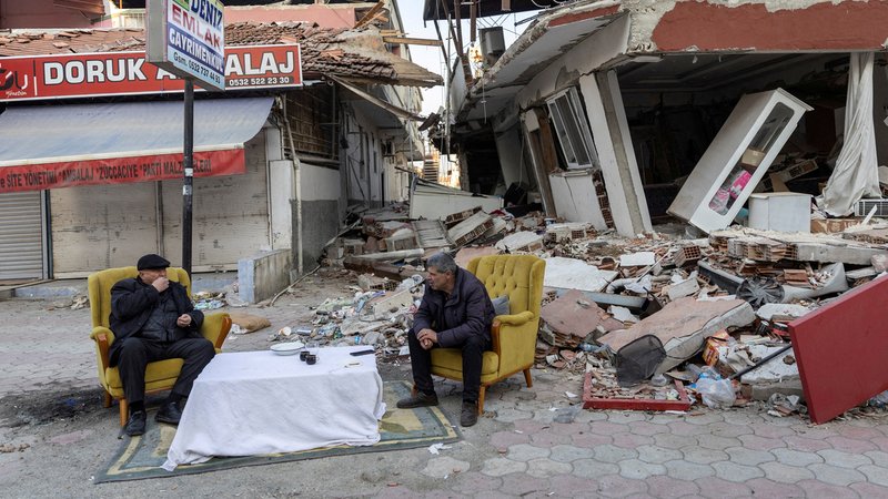 Männer sitzen und unterhalten sich vor zerstörten Häusern nach dem tödlichen Erdbeben in Antakya, Provinz Hatay (Archivbild)