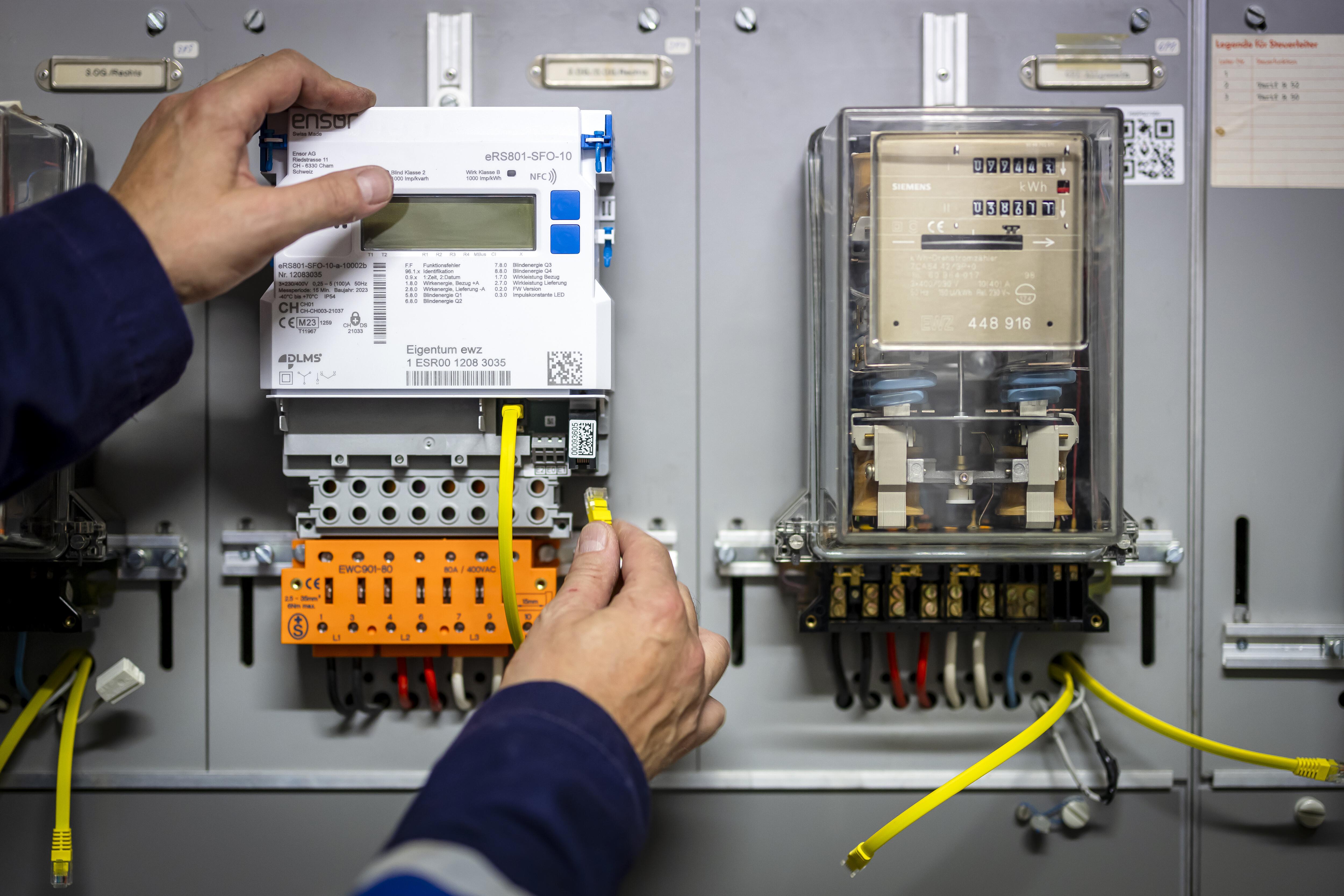 Ein Zählermonteur installiert einen Smart-Meter-Stromzähler neben einem alten Stromzähler.