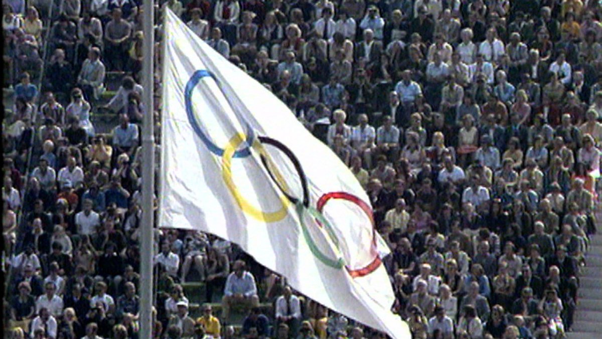 Publikum im Münchner Olympiastadion 1972 mit Olympiaflagge im Vordergrund
