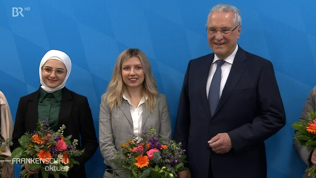 Innenminister Joachim Herrmann (CSU) neben zwei Frauen. | Bild: BR Innenminister Joachim Herrmann (CSU) neben zwei Frauen.
