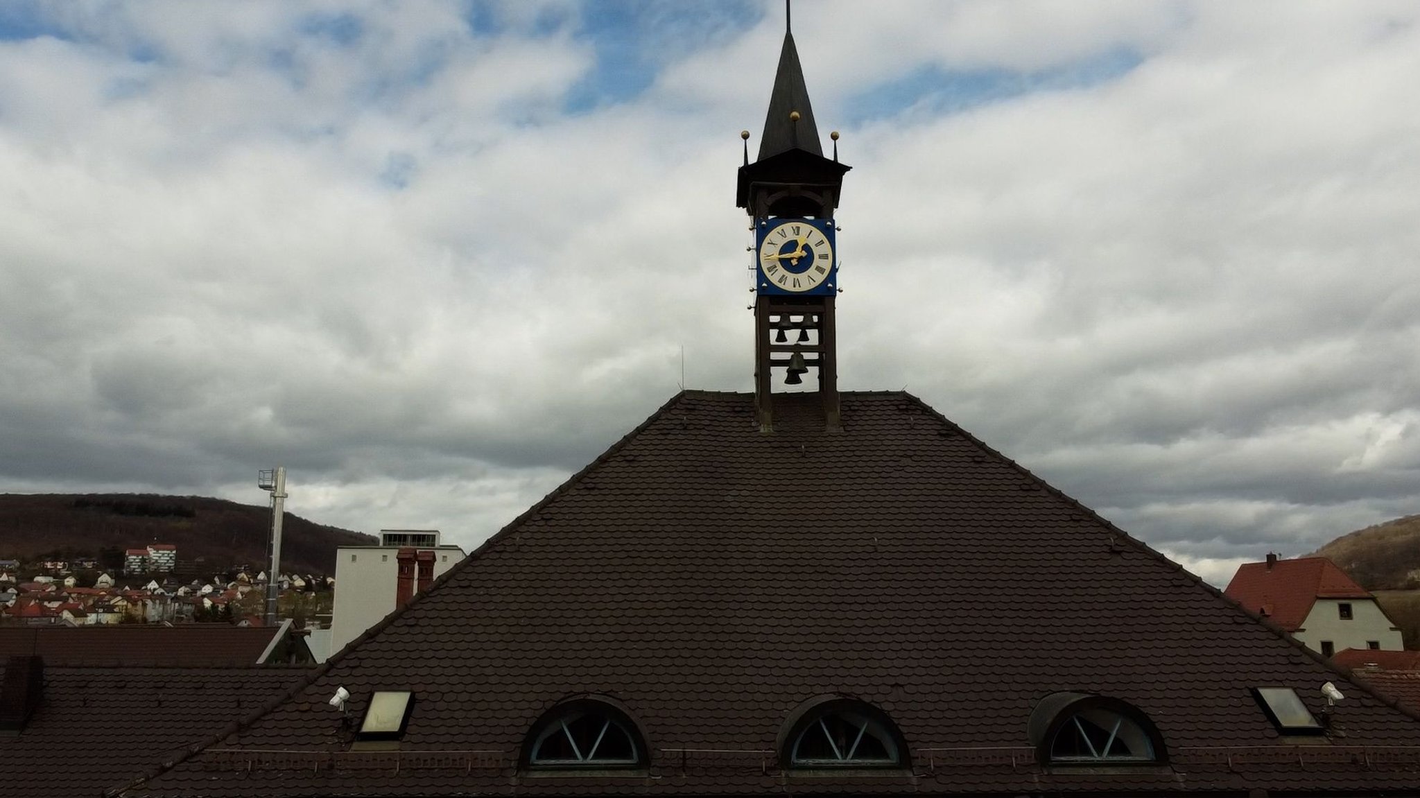 Das Rathausdach in Treuchtlingen mit einer Uhr und Glocken.