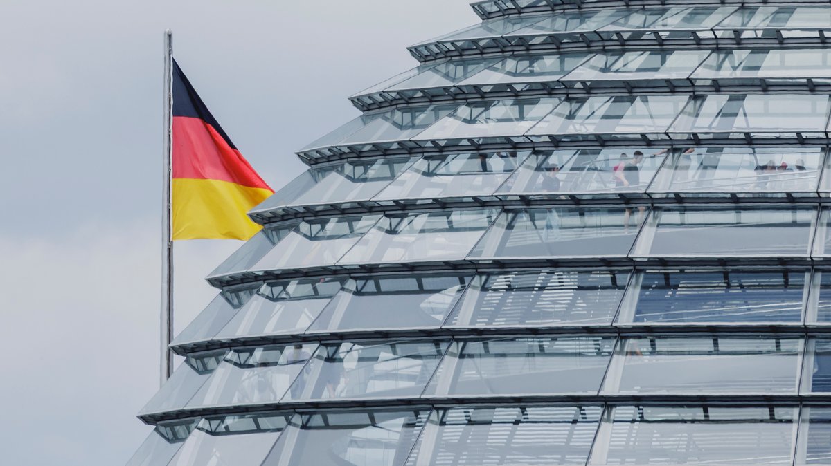 Deutschlandfahne neben der Kuppel des Reichtagsgebäudes.