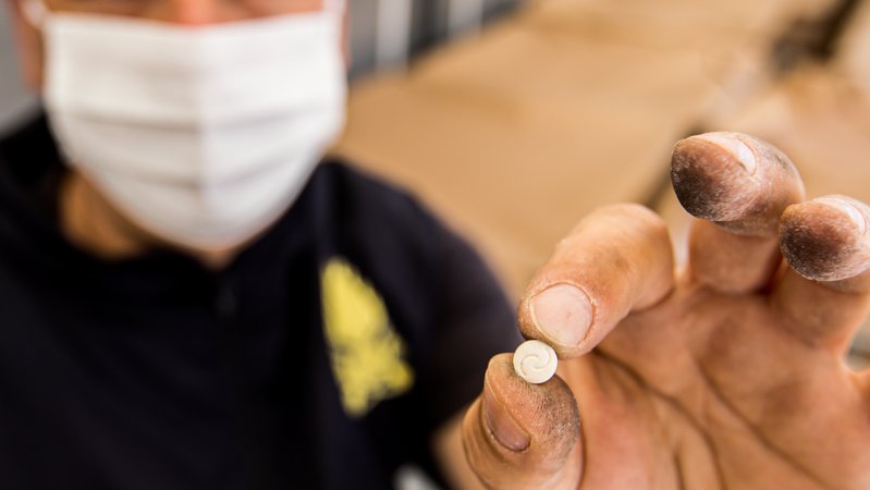 Ein Mann hält eine Captagon-Tablette mit typischem Logo zwischen den Fingern. | Bild: pa/FOTOGRAMMA/napolipress Ein Mann hält eine Captagon-Tablette mit typischem Logo zwischen den Fingern.