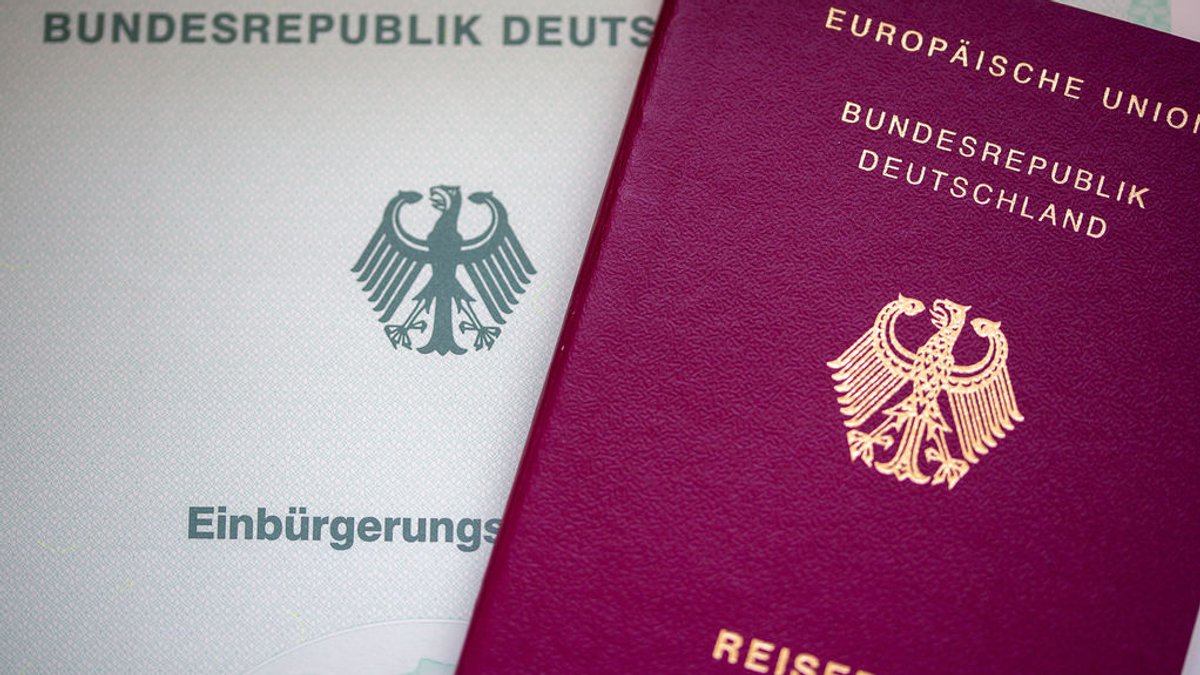 Eine Einbürgerungsurkunde der Bundesrepublik Deutschland (l) und ein deutscher Reisepass liegen auf einem Tisch.  (Symbolbild)