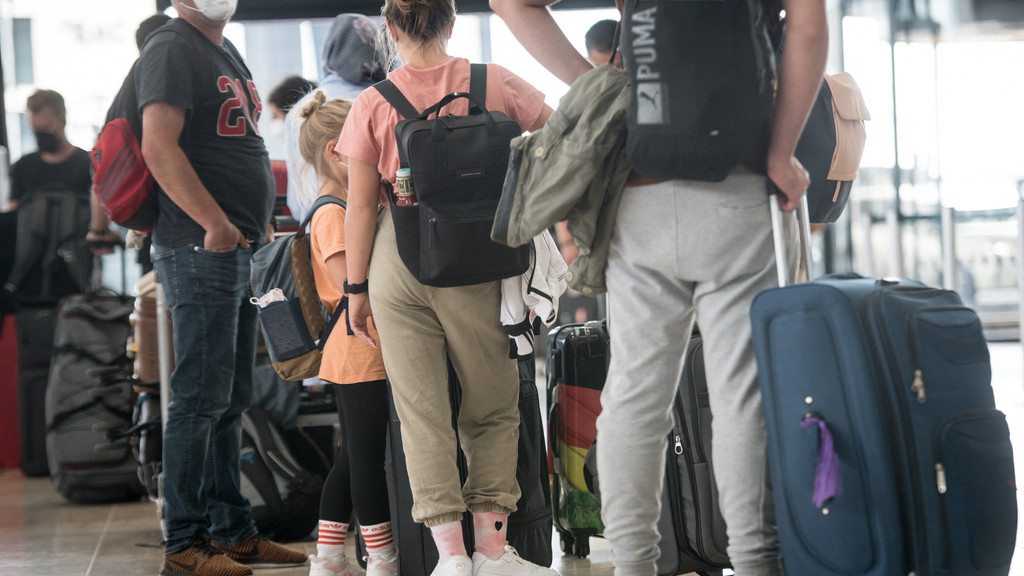 Urlauber stehen Schlange, um ihre Koffer an einem Check-in-Schalter des Willy-Brandt-Flughafen in Berlin aufzugeben.
