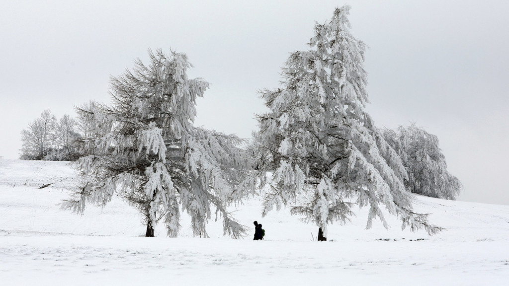 Eine Spaziergängerin ist auf einem schneebedeckten Weg unterwegs.